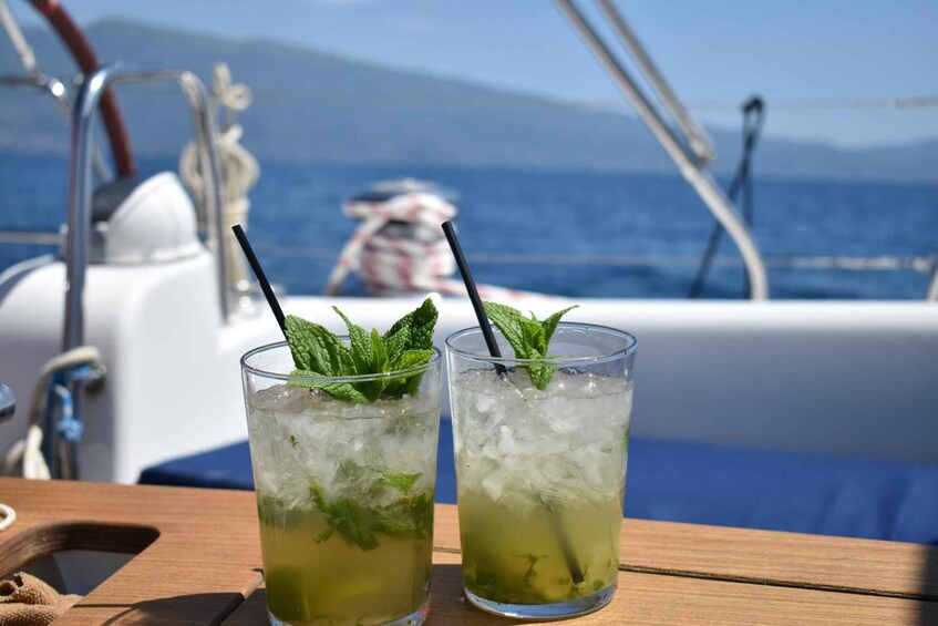 Two glasses of green cocktail with mint leaves on a boat deck. 2