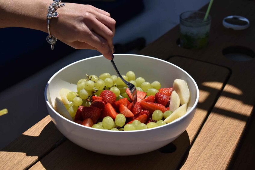 A bowl of fruit salad with grapes, strawberries, and bananas. 4