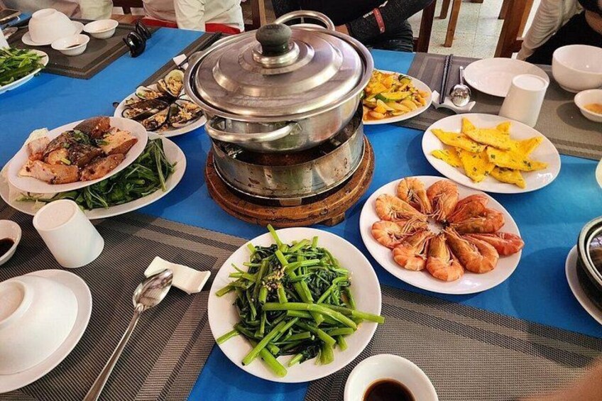 A table with various dishes, including seafood and vegetables, and a hot pot in the center. 2