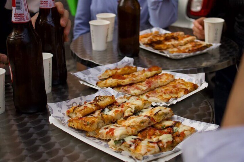 Et bord med pizzastykker og flasker med øl. 1