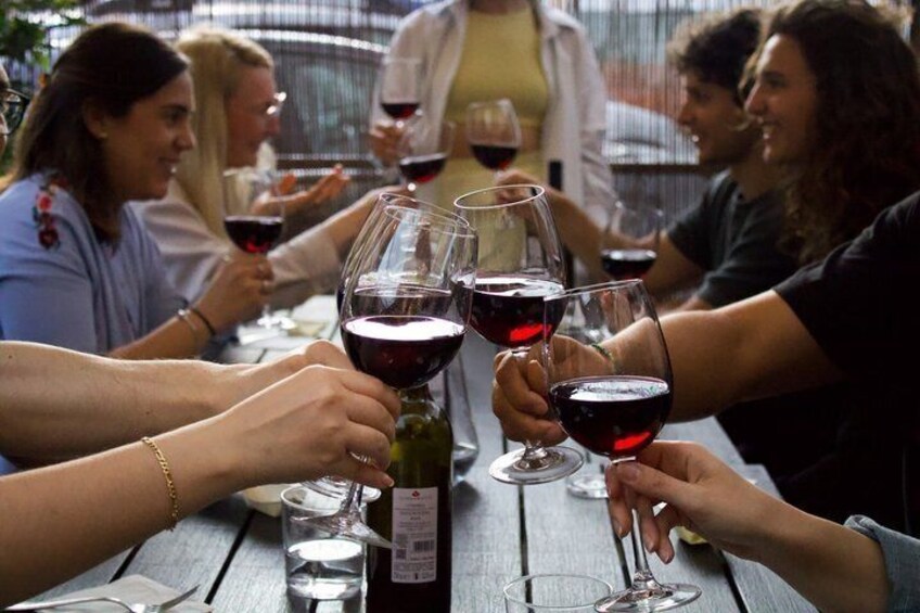 Un grupo de personas brindando con copas de vino en una mesa de madera al aire libre. 2
