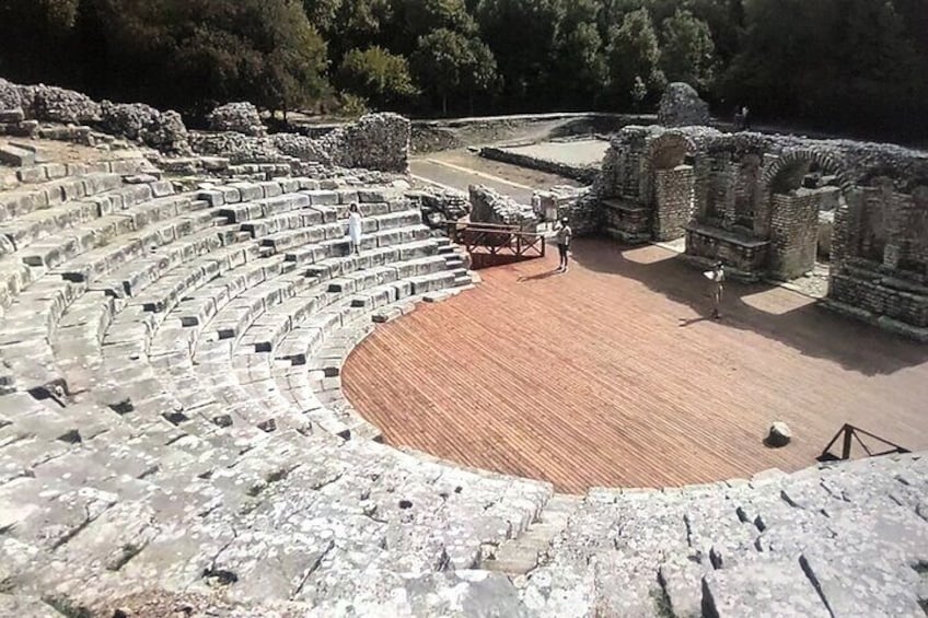 An ancient amphitheater with stone seating and a wooden stage. 3