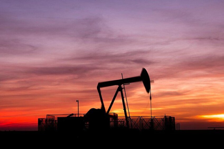 A silhouette of an oil pumpjack against a sunset sky. 4