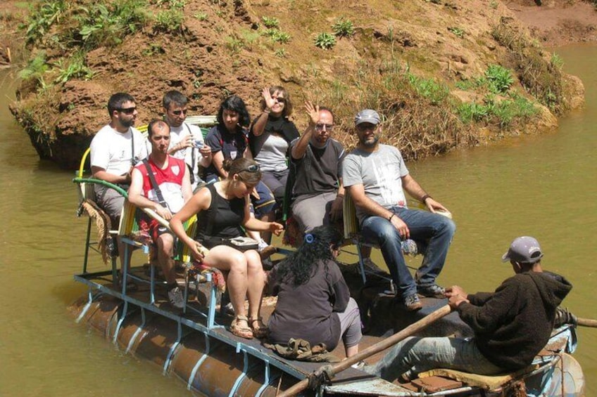 Un grupo de personas en una barca que navega por un canal estrecho, rodeado de follaje y una orilla embarrada. 2