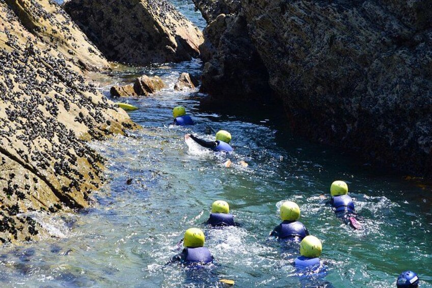 A group of people in water with yellow helmets, swimming in a rocky river. 3
