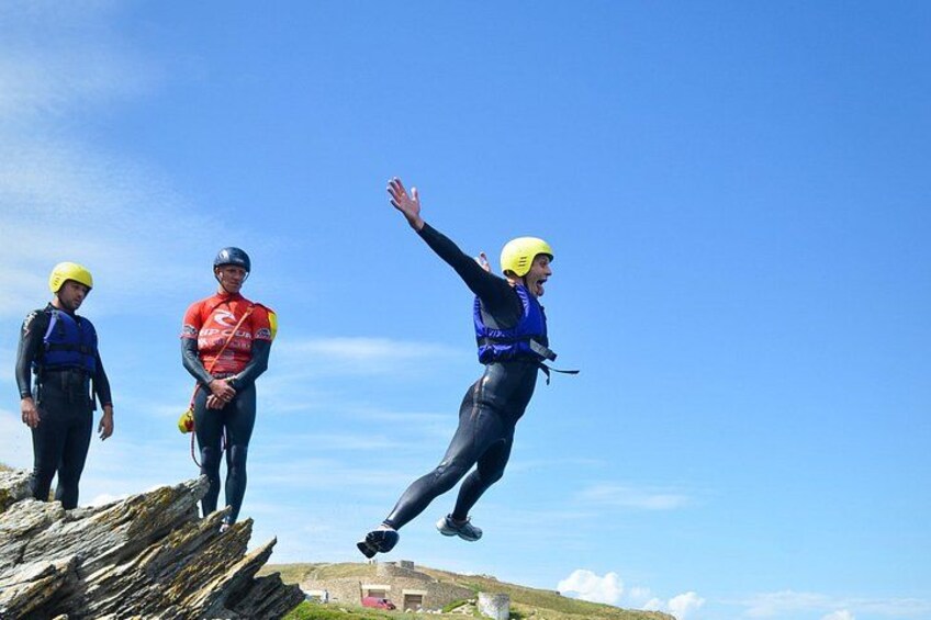 Three individuals in helmets and safety gear on a rocky outcrop with a clear sky. 4