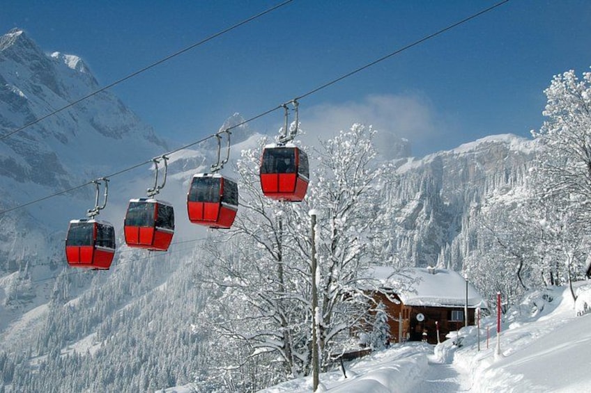 Un télésiège avec des cabines rouges, sur fond de montagne enneigée. 2