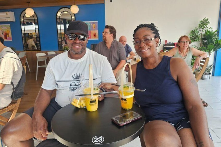 Two people sitting at a table with drinks and a phone. 2