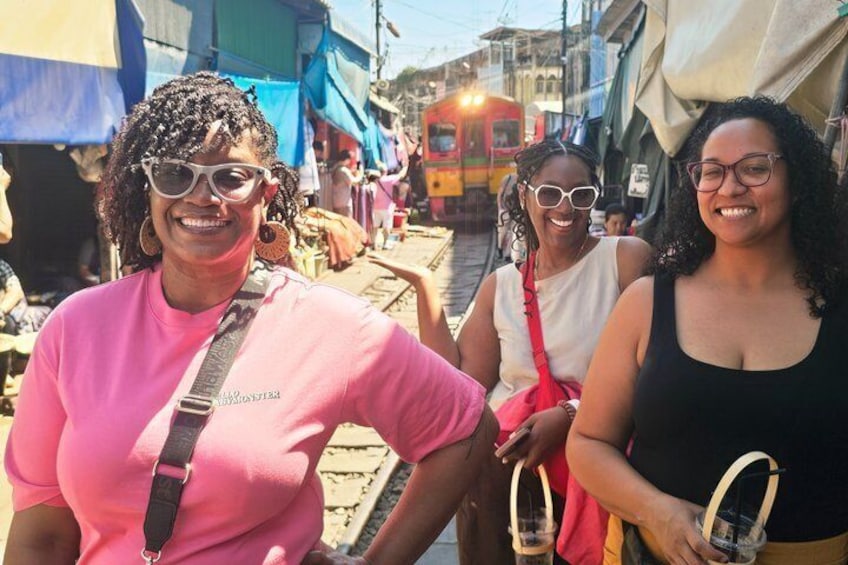 A street market with people and a train in the background. 1