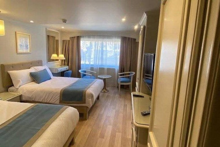 A hotel room with two beds, a desk, a chair, and a TV. 5