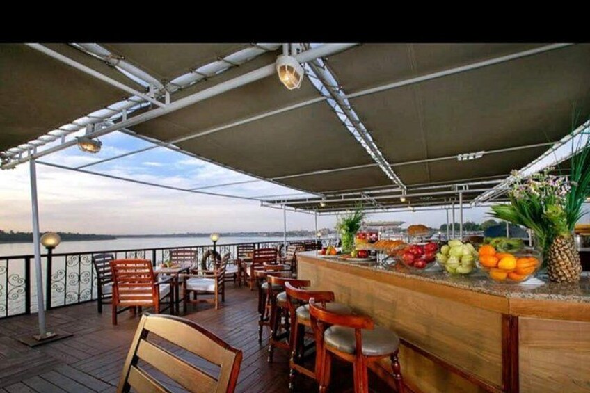 An outdoor bar area with wooden furniture and a fruit display. 2