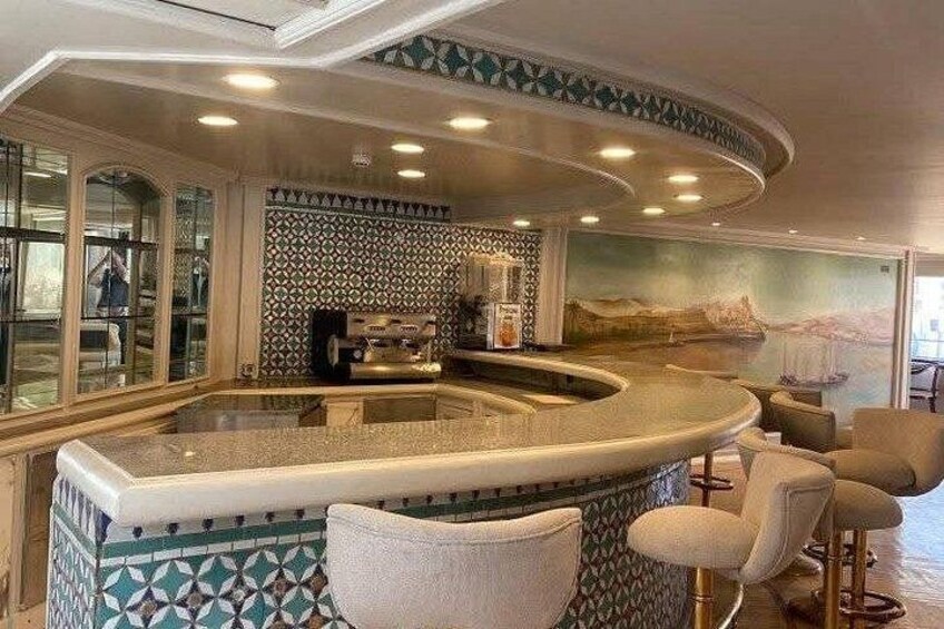 A bar area with a curved counter, patterned tiles, and bar stools. 4