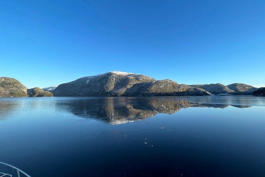 Een rustig meer met heldere weerspiegelingen van verre bergen onder een blauwe lucht. 5
