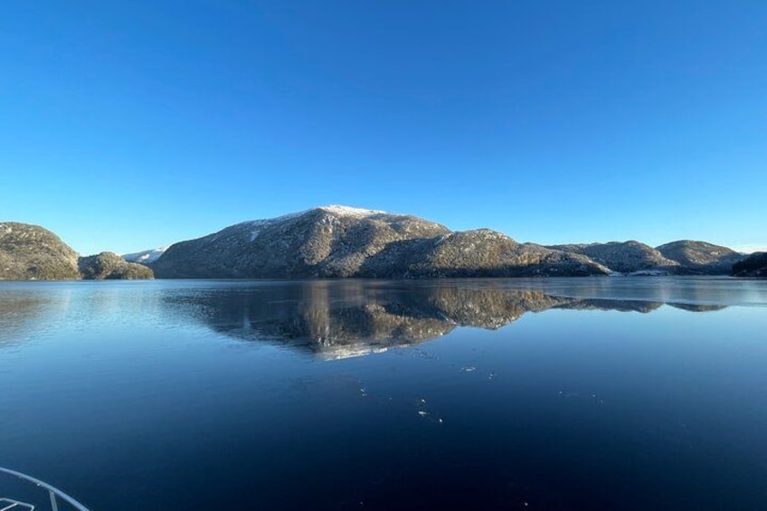 Un lago tranquilo con reflejos nítidos de montañas bajo un cielo azul. 5