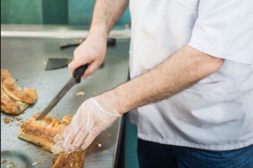 Una persona con camisa y guantes blancos usa una espátula para manipular alimentos en una parrilla. 4