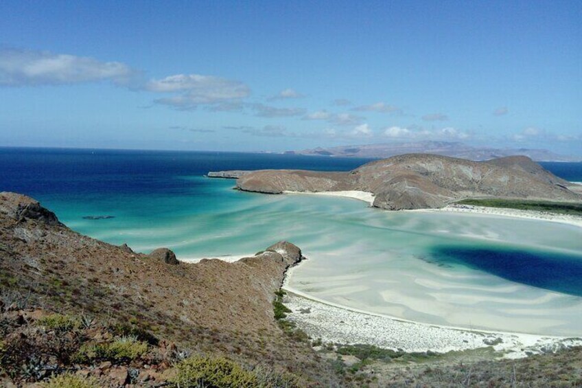 A coastal landscape with clear turquoise waters, sandy beaches, and rocky outcrops. 3