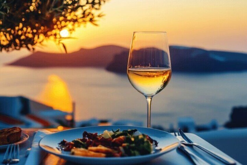 Een tafel met een bord eten en een glas witte wijn, met uitzicht op een wateroppervlak bij zonsondergang. 1
