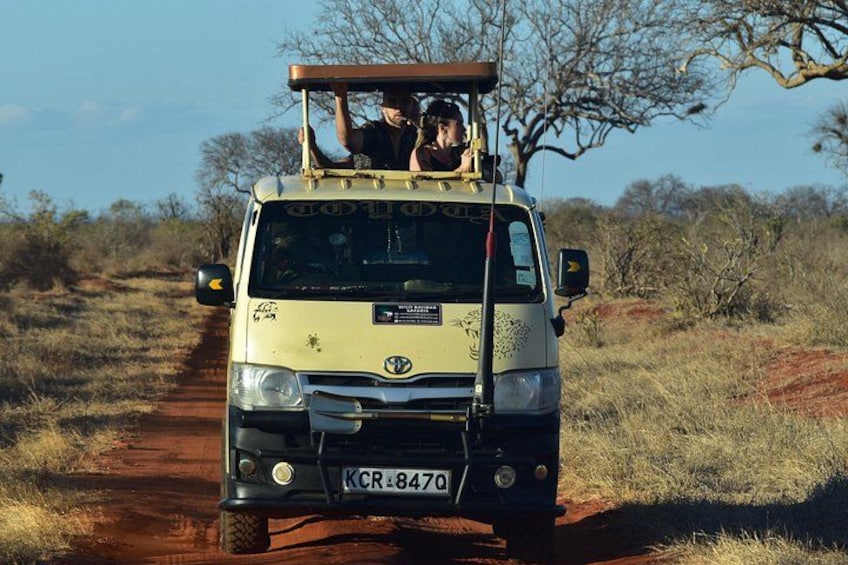 A safari vehicle on a dirt road with passengers. 3