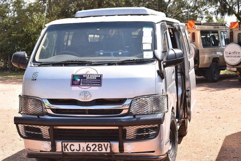 A white Toyota Land Cruiser with a license plate KCJ 628V, parked on a dirt road with trees in the background. 1