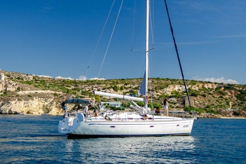 A sailboat on calm waters with a rocky coastline in the background. 2