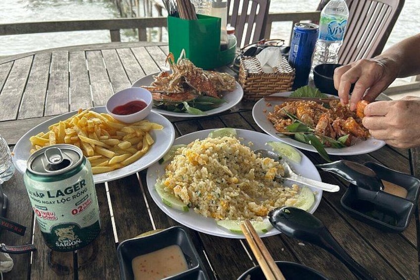 A wooden table with plates of food, a can of beer, and a bottle of water. 3
