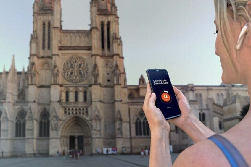 A person holding a smartphone with a cathedral in the background. 5