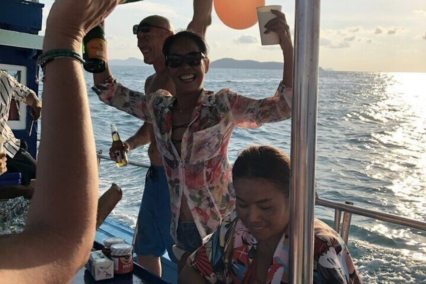 People on a boat, holding drinks and a balloon. 4