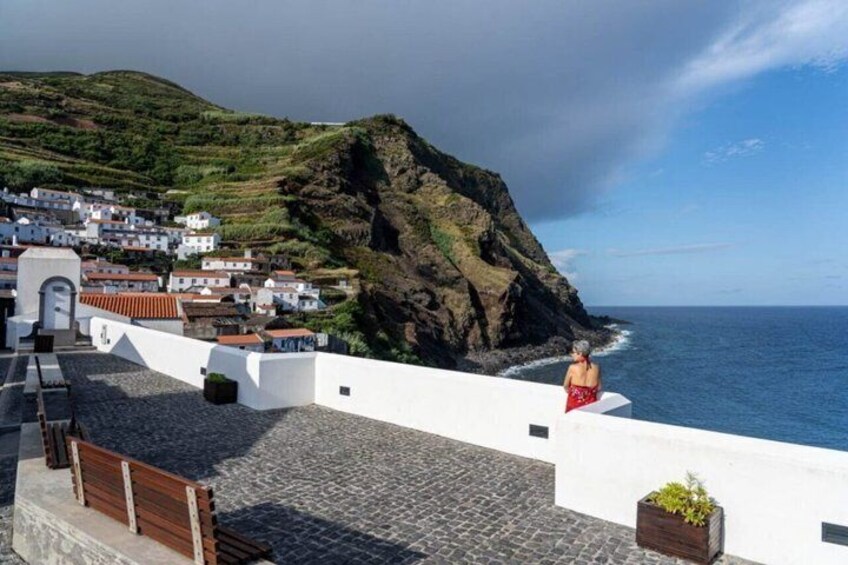 A coastal town with white buildings, a rocky cliff, and the ocean. 4