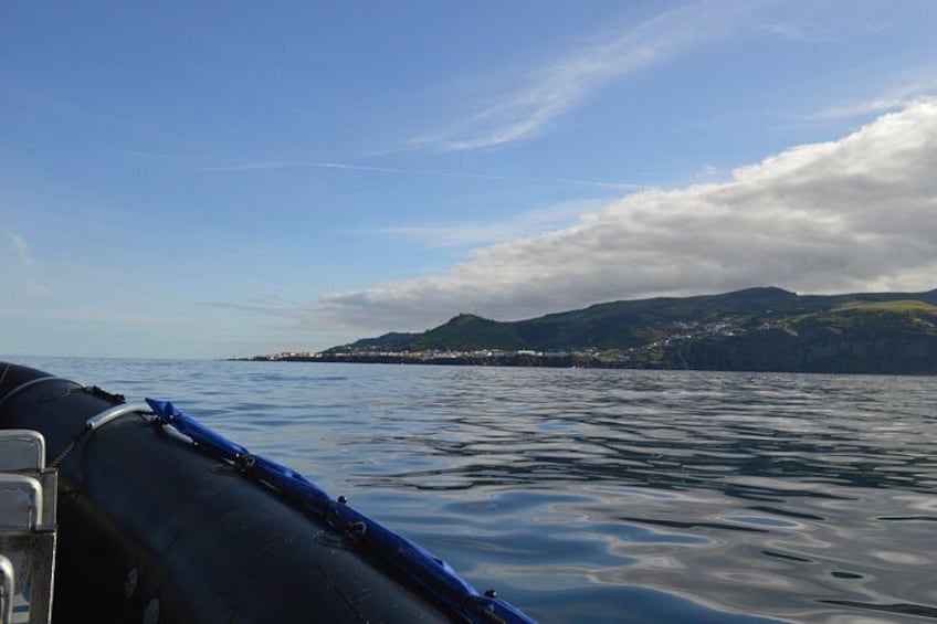 A boat on calm water with a mountainous coastline in the background. 3