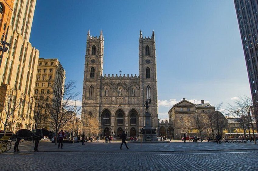 A historic church with twin towers, a cobblestone plaza, and modern buildings. 3