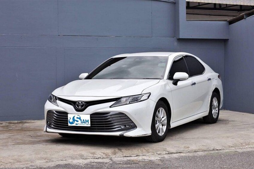 Ein weißer Toyota-Sedan vor einem blauen Gebäude. 2