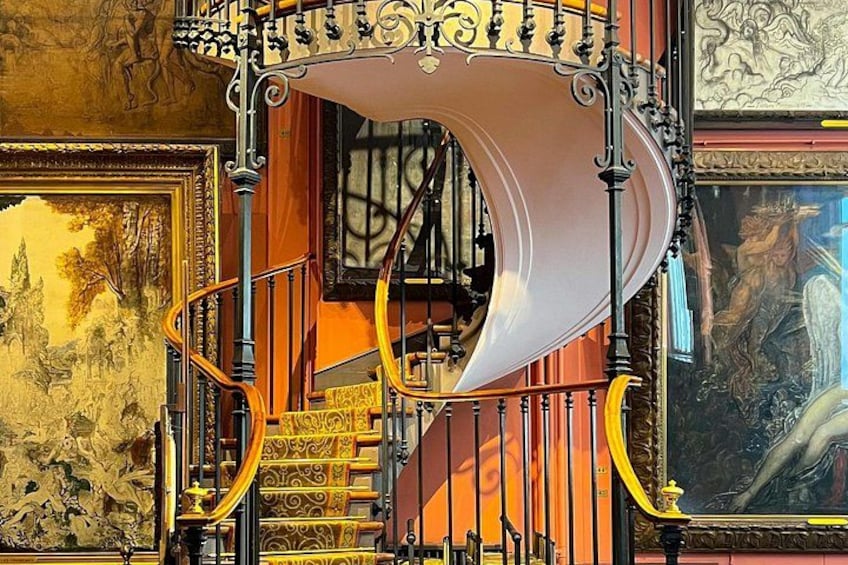 En spiraltrappa med utsmyckade metallräcken och guldfärgade detaljer. 3
