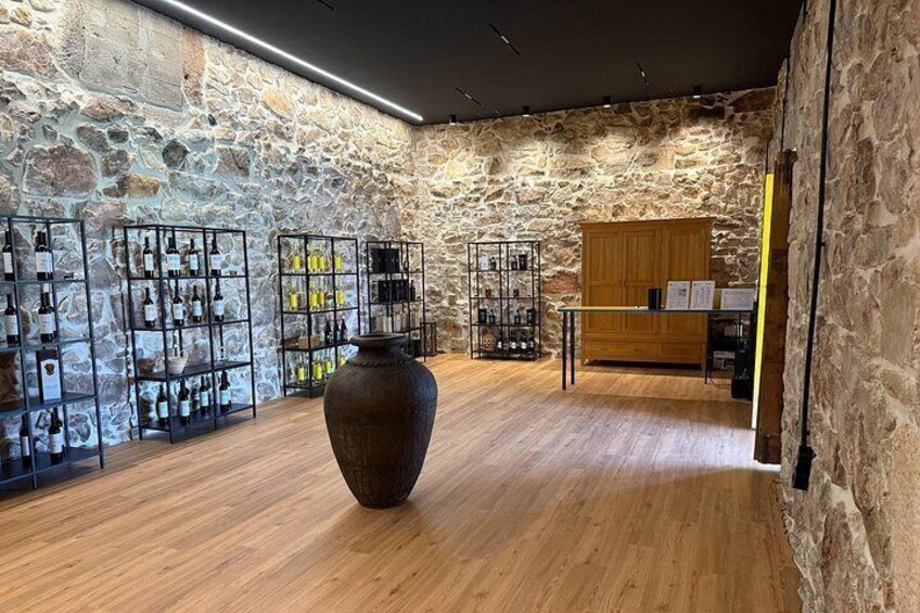 A stone wall interior with wooden flooring, metal wine racks, and a large vase. 2
