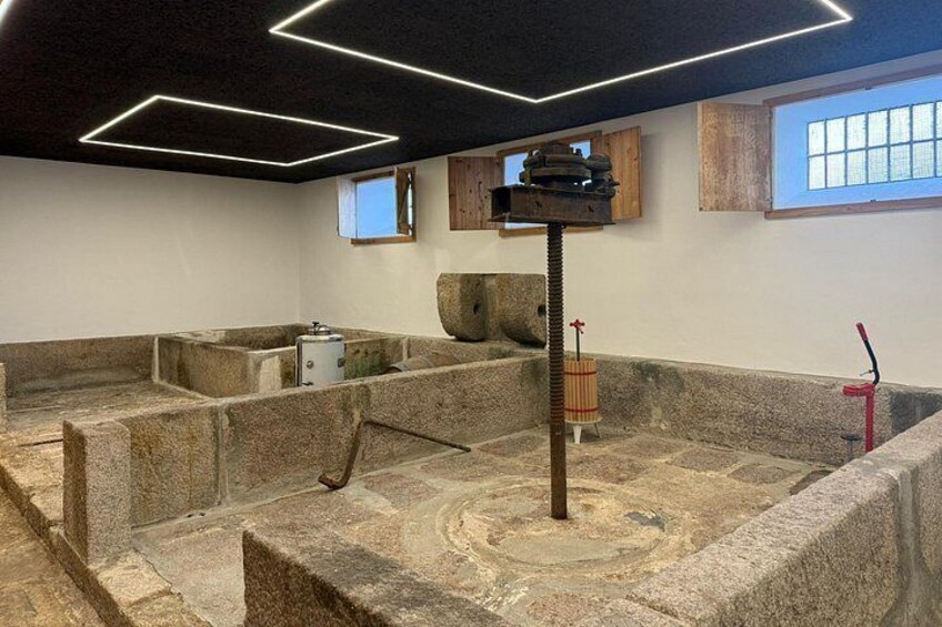A stone bathhouse with a central pillar, stone benches, and a wooden shelf with objects. 3
