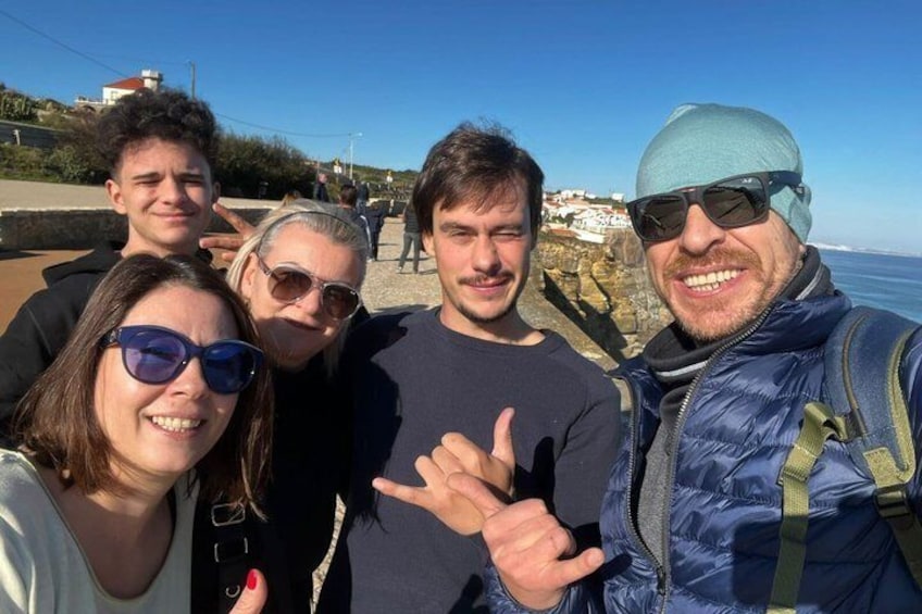 Un groupe de personnes posant près d’une zone côtière, avec un ciel dégagé et un paysage rocheux. 3