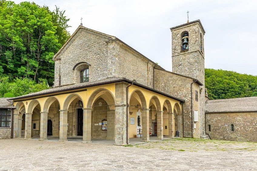 A historic stone building with a bell tower, arched walkways, and a courtyard. 1