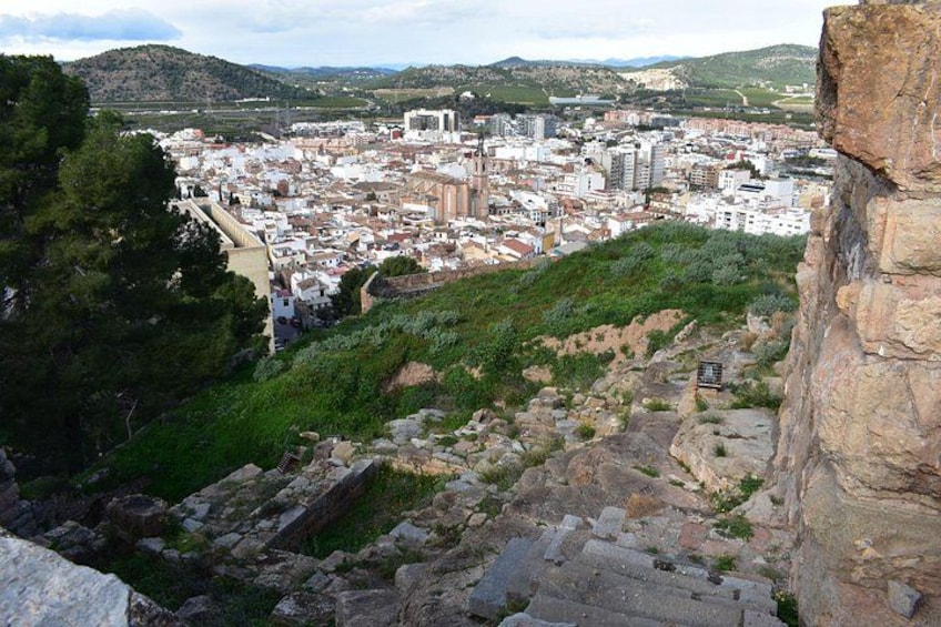 A cityscape with ancient ruins, a modern building, and a mountainous backdrop. 2