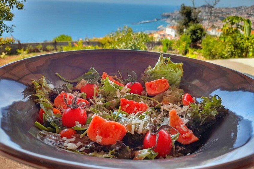 Ensalada con tomates y hojas verdes, frente a un pintoresco paisaje costero. 4
