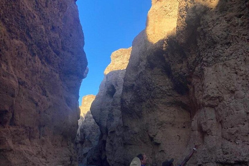 A narrow canyon with steep rock walls and a clear blue sky. 4