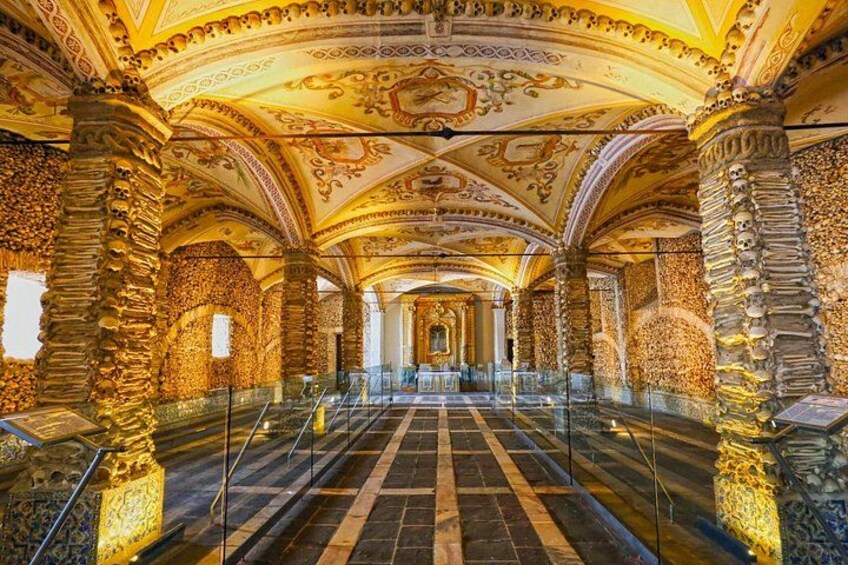 Un interior ornamentado con techo abovedado, columnas de piedra y piso de tablones en damero. 4
