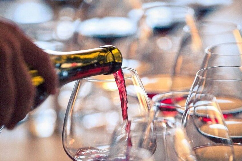Una mano vertiendo líquido rojo en una copa de vino. 1