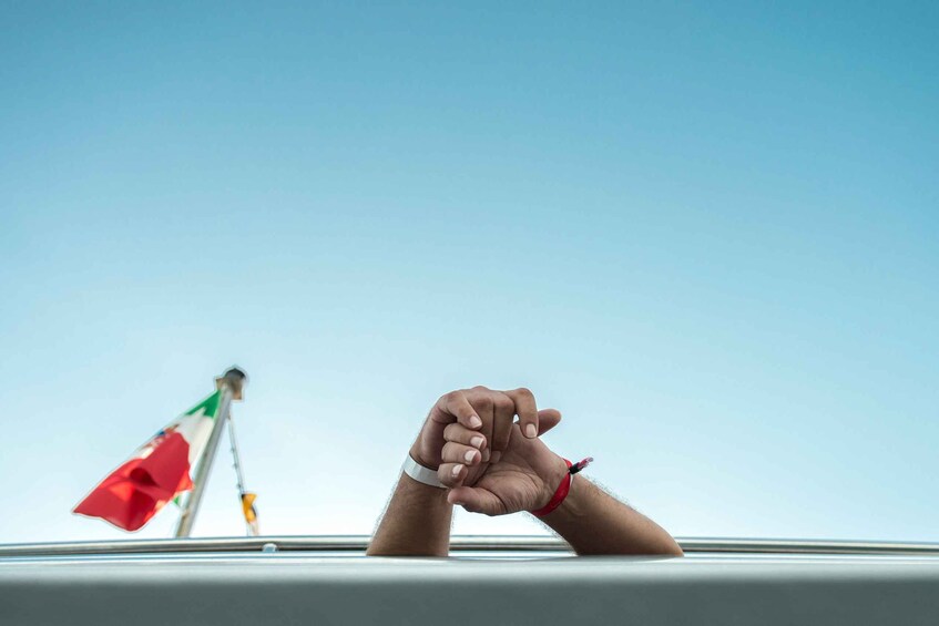 A hand resting on a railing with a flag in the background. 3