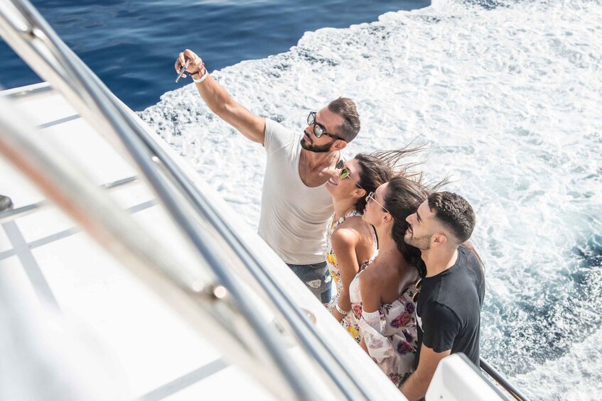 A group of people on a boat with a railing and ocean waves in the background. 1