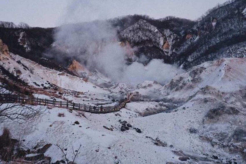 A snow-covered landscape with a wooden fence and steam rising from the ground. 2