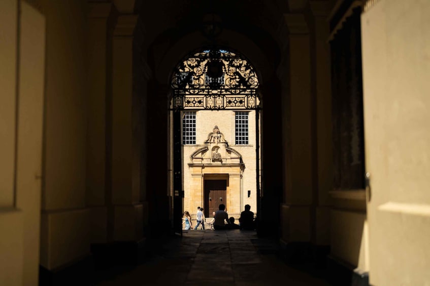 A corridor with an ornate archway leading to a building with a statue and a door. 3