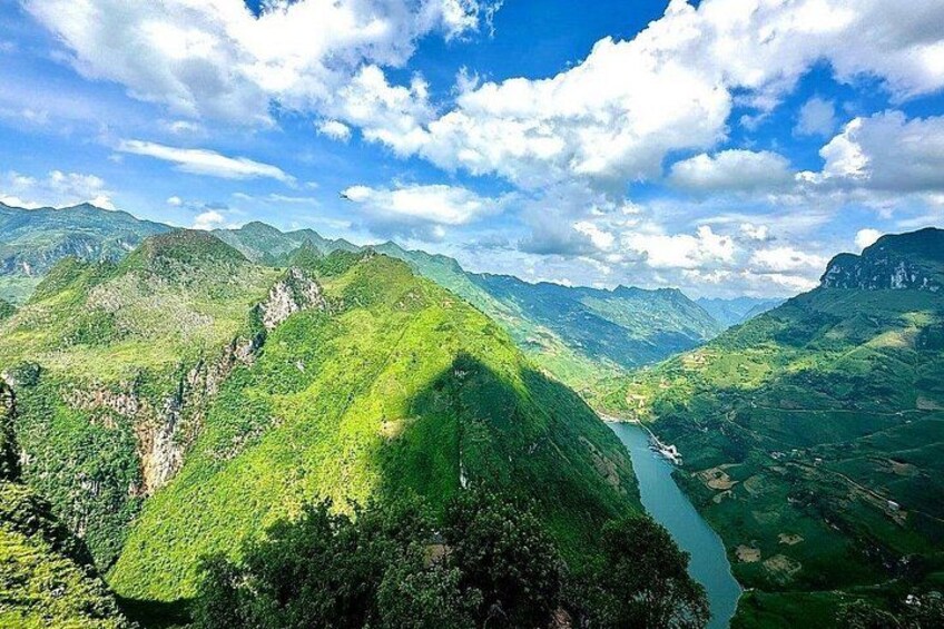 A mountainous landscape with a river, lush greenery, and a clear sky. 3