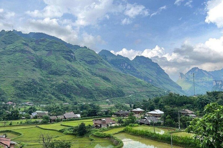 A village nestled in a valley with terraced rice fields, surrounded by lush green mountains. 5