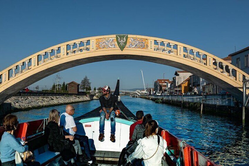 Un paseo en barco bajo un puente, con pasajeros y un guía. 2