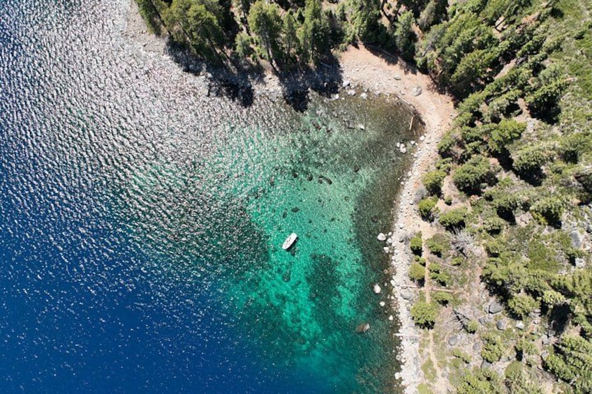 Un bote en un mar turquesa con una costa rocosa y árboles verdes frondosos. 4