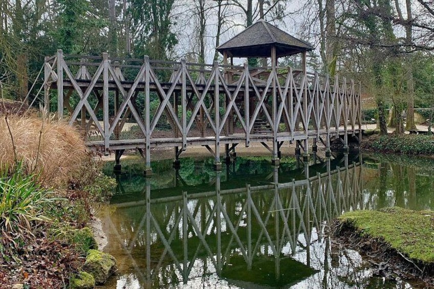 Un puente de madera con un mirador, rodeado de agua y vegetación. 5